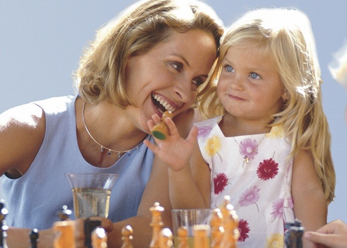 Mother and daughter playing chess with healthy smiles thanks to preventive dentistry