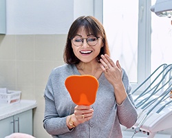 Female dental patient checking smile in mirror