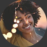 Smiling young woman outdoors with string lights in front of her