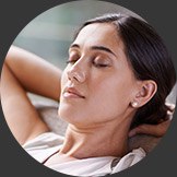 Woman laying back with eyes closed and hands behind head