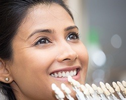 Woman's smile compared with porcelain veneer color chart