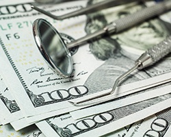 dental instruments sitting below a stack of money