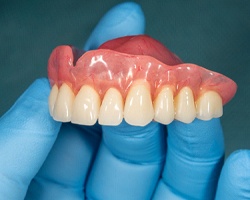Gloved hand holding dentures in Louetta Texas