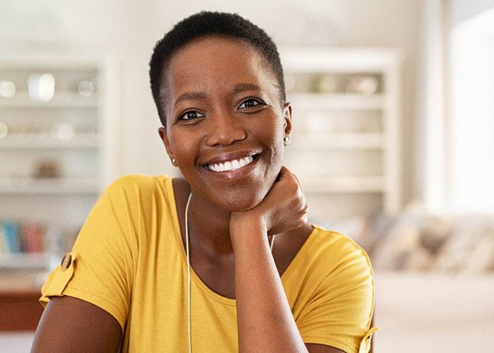 Woman in yellow shirt smiling at home in living room