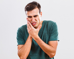 man in green shirt with toothache in need of emergency dentistry