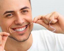 man flossing his teeth