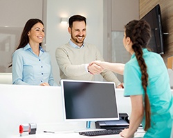 A younger couple arrive for a consultation with an implant dentist to discuss the potential for permanent dental implants