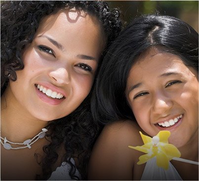 Mother and daughter smiling with a yellow flower in the foreground