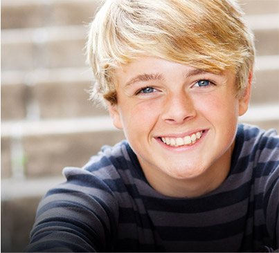 Young boy in striped shirt smiling in front of staircase