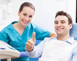 Smiling man in dental chair gives a thumbs up