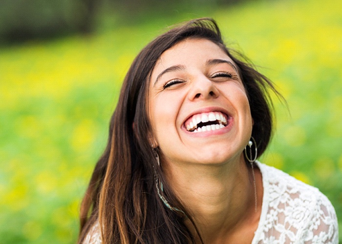 Woman with porcelain veneers smiling outside