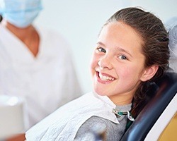 Young girl smiling in dental chair after fluoride treatment