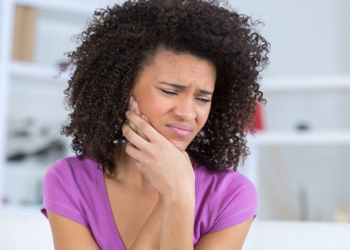 Woman holding jaw in pain needs TMJ therapy