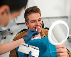 Man using dental mirror to examine his veneer shades