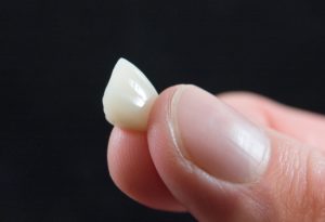 Fingers pinching dental crown