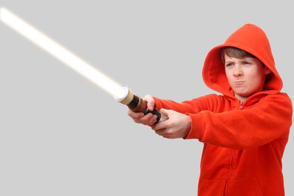 A little boy playing with a lightsaber laser toy.
