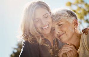 Older woman leaning head on shoulder of younger smiling woman